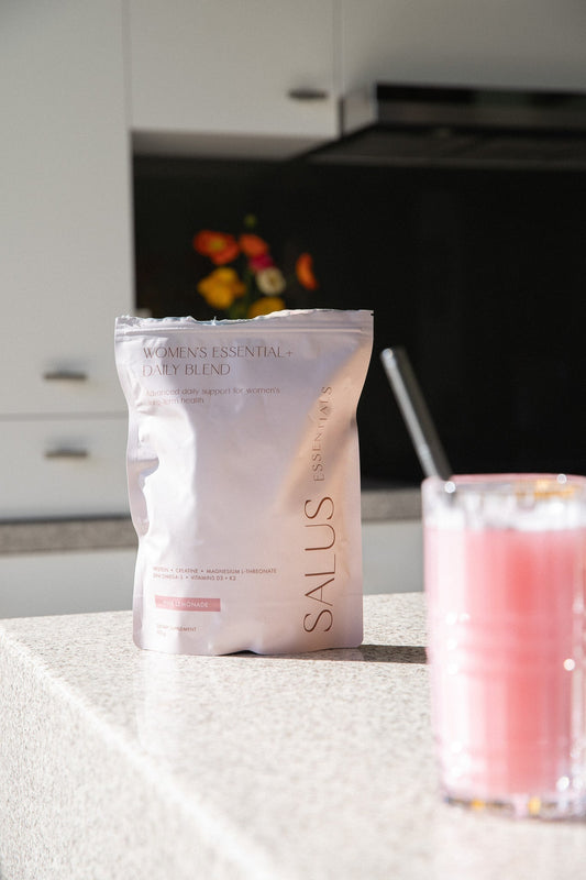 A clear glass of Salus pink lemonade — a light protein water, not a milky shake